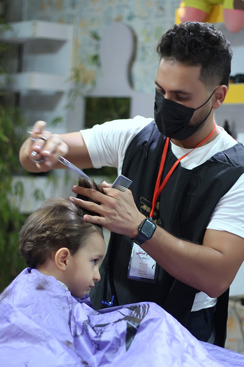 بهنام فیاض در حال اصلاح موی کودکان