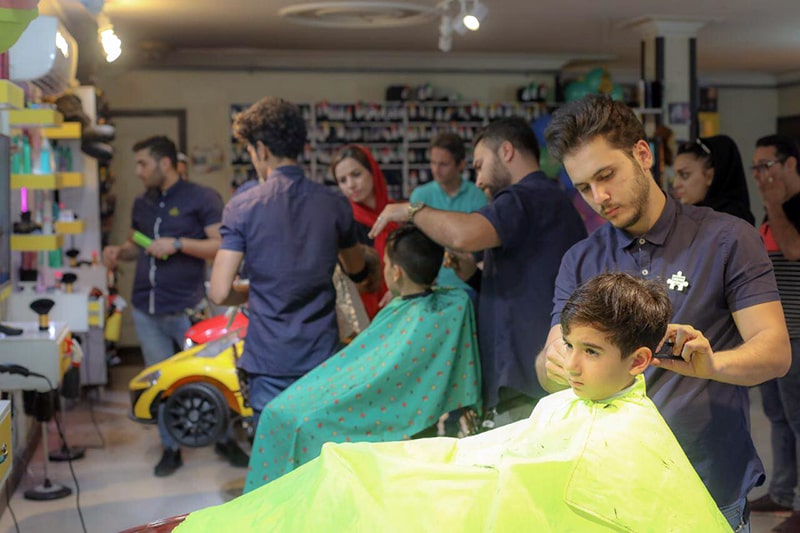 بهنام فیاض در حال اصلاح موی کودک در آرایشگاه پازل